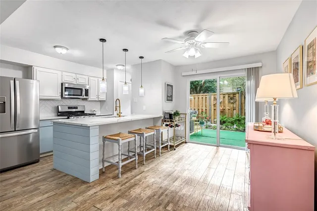 a kitchen with stainless steel appliances granite countertop a refrigerator a stove top oven a sink dishwasher and white cabinets with wooden floor