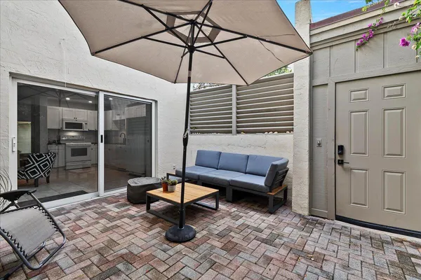 a backyard of a house with table and chairs under an umbrella