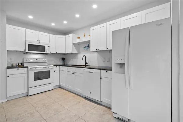 a kitchen with stainless steel appliances granite countertop white cabinets and refrigerator