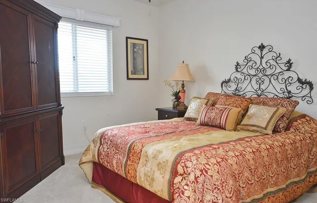 a bedroom with a bed and a lamp on dresser