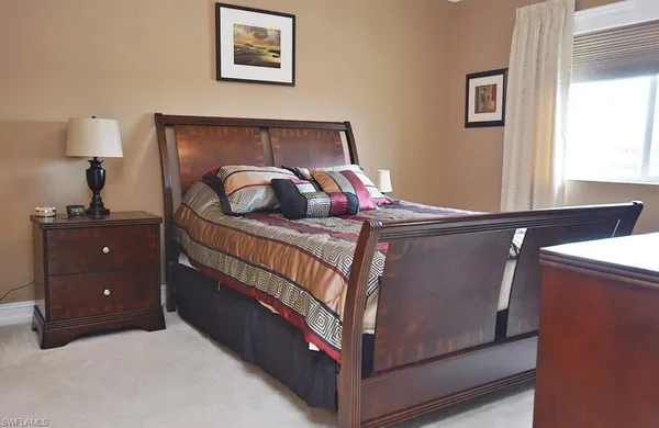 a bedroom with a bed and a lamp on dresser