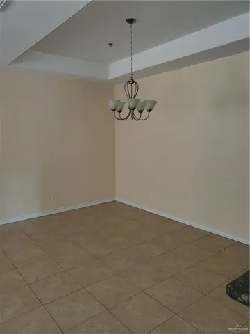 a view of a room with a hanging light and kitchen view