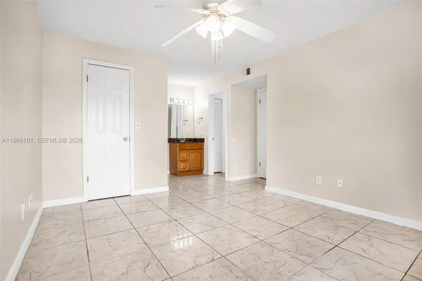 a view of an empty room with window and chandelier fan