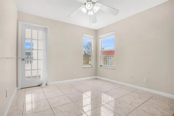 a view of an empty room with window and chandelier fan