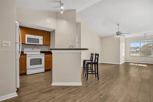 a kitchen with stainless steel appliances granite countertop a stove top oven a sink dishwasher and a refrigerator with wooden floor