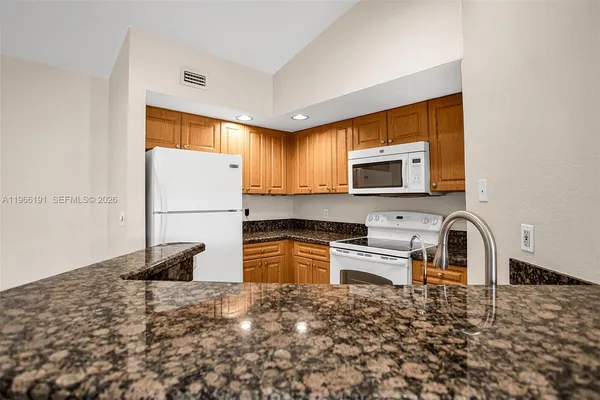 a kitchen with granite countertop a refrigerator and a stove top oven