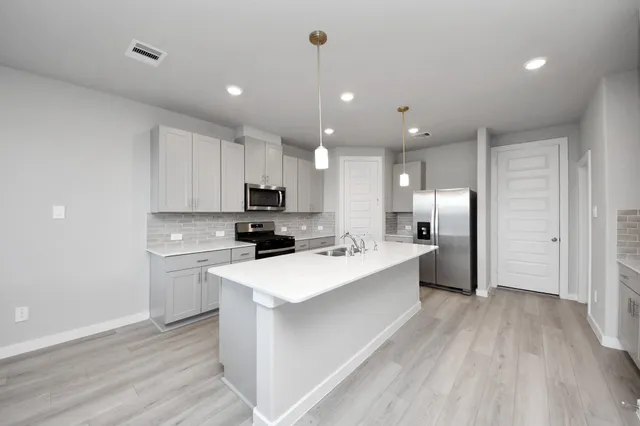 a large kitchen with kitchen island a sink a center island stainless steel appliances and a counter space