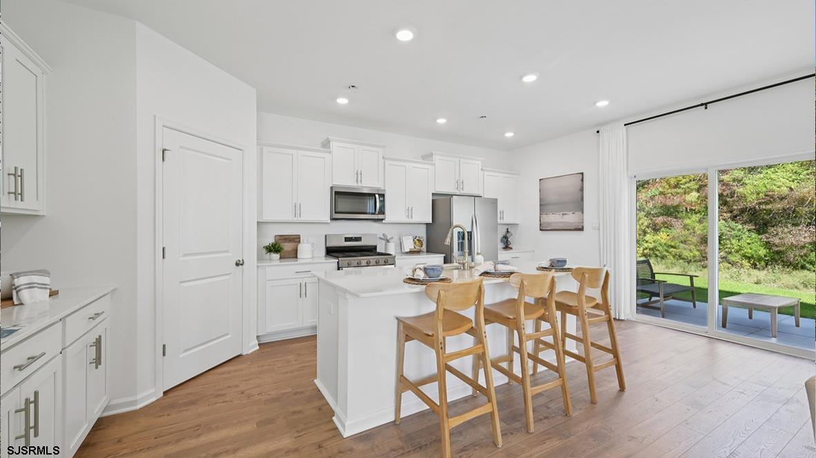 507 Scotty Boulevard, Unit 1301 Rio Grande, NJ 08242 - Photo 18 of 42 a kitchen with stainless steel appliances kitchen island granite countertop a stove top oven a sink a refrigerator with white cabinets and wooden floor