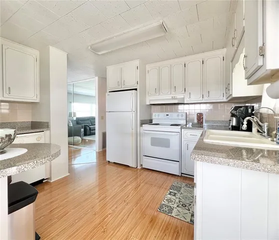 a kitchen with granite countertop white cabinets and white appliances