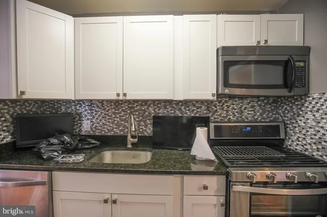 a kitchen with granite countertop a sink stainless steel appliances and cabinets