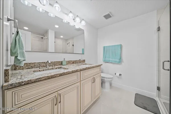a bathroom with a granite countertop sink mirror and a toilet