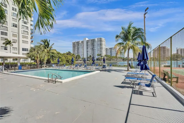 a view of a swimming pool with a lawn chairs and palm tree