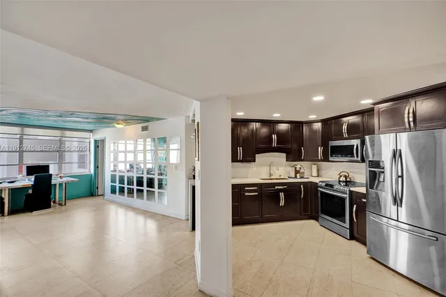 a kitchen with stainless steel appliances kitchen island granite countertop a refrigerator and a stove top oven