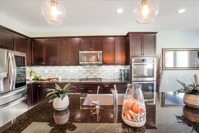 a kitchen with stainless steel appliances granite countertop a sink a stove and refrigerator