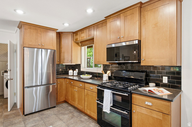 1709 Meadowmoor Road Holladay, UT 84117 - Photo 11 of 32 Recessed lighting illuminates wood cabinetry, stainless steel appliances, black tile backsplash, and dark countertops