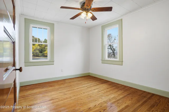 a view of empty room with wooden floor and fan