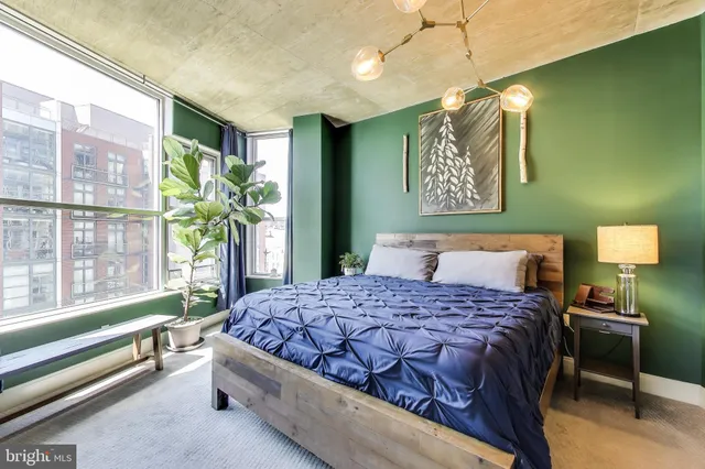 a bedroom with a bed and a lamp on dresser