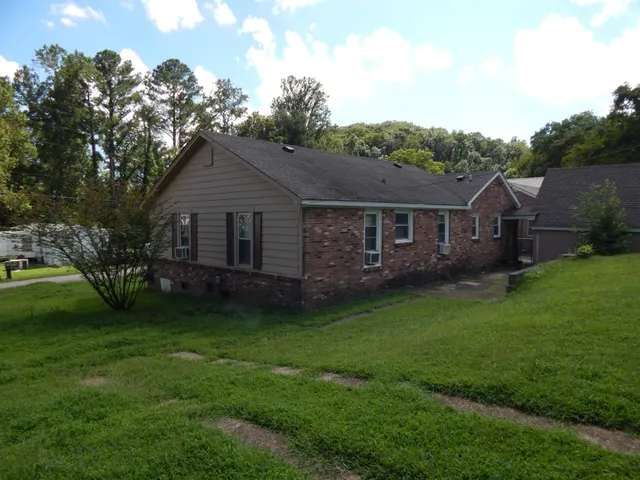 a view of a house with a big yard potted plants and large tree