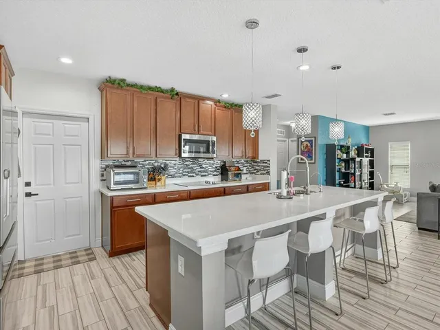 a room with stainless steel appliances kitchen island granite countertop a table chairs and a refrigerator