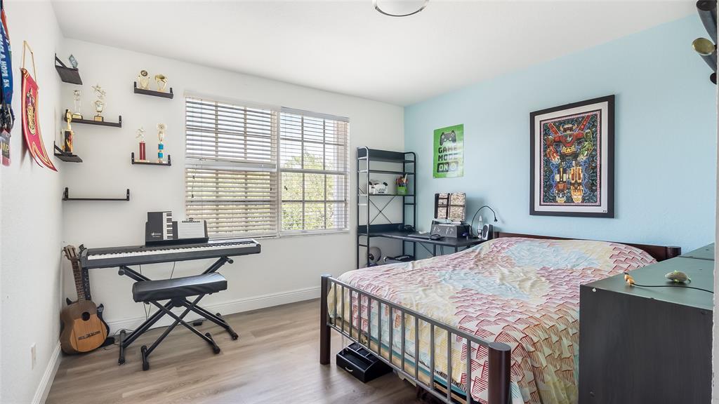 19470 Stonebrook Street Weston, FL 33332 - Photo 34 of 44 a bedroom with a bed and a table in it with wooden floor