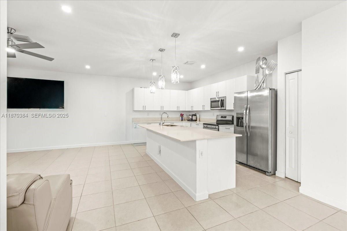 19803 Southwest 321st Street Homestead, FL 33030 - Photo 17 of 48 a large white kitchen with cabinets a sink a window and stainless steel appliances