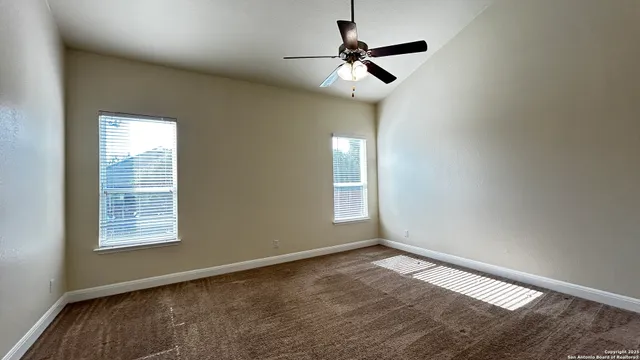 en empty room with windows and ceiling fan