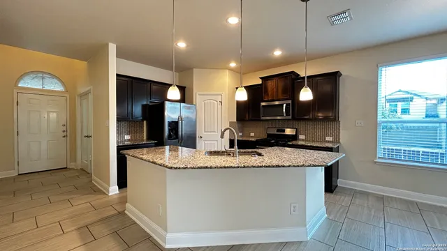 a kitchen with stainless steel appliances granite countertop a sink a stove and a refrigerator