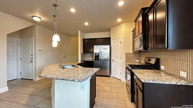 a kitchen with granite countertop kitchen island stainless steel appliances a sink stove and refrigerator