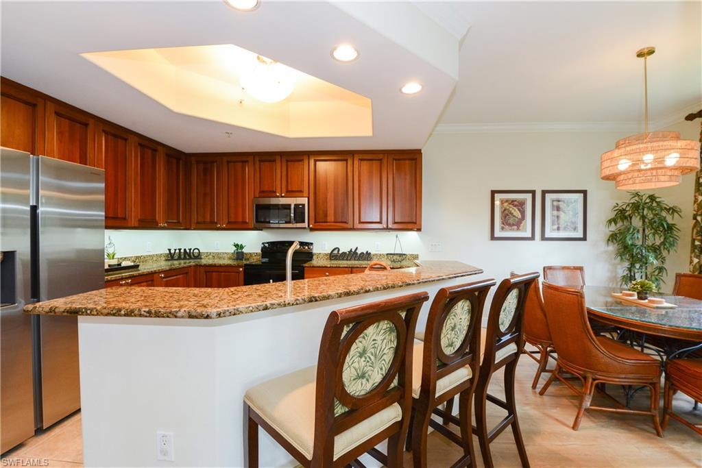 975 Sandpiper Street, Unit A104 Naples, FL 34102 - Photo 8 of 33 a kitchen with a table chairs sink and cabinets