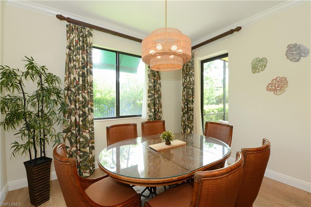 975 Sandpiper Street, Unit A104 Naples, FL 34102 - Photo 9 of 33 a dining room with furniture a chandelier and wooden floor