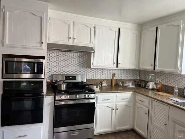 a kitchen with granite countertop white cabinets and stainless steel appliances