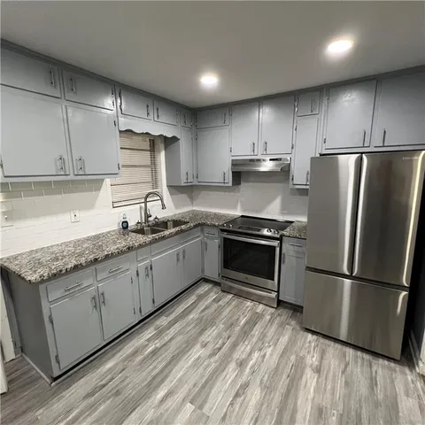 a kitchen with granite countertop a refrigerator sink and stove