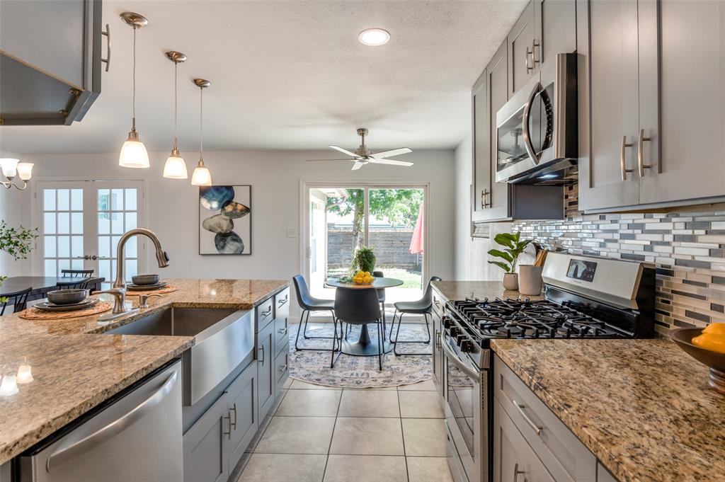 a kitchen with a stove a sink a refrigerator and chairs
