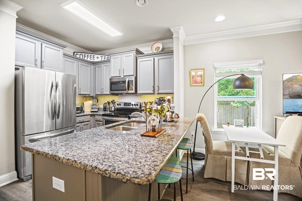 25806 Pollard Road, Unit 27 Daphne, AL 36526 - Photo 17 of 46 Kitchen featuring stainless steel appliances, light stone countertops, a kitchen breakfast bar, gray cabinets, and crown molding