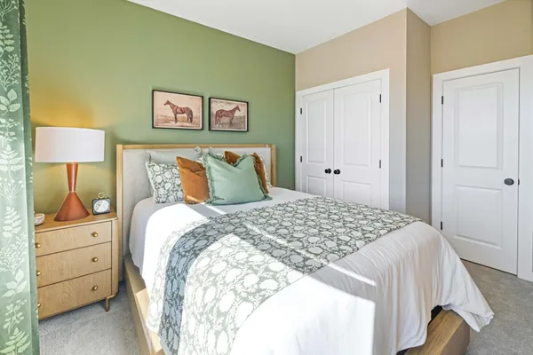 a bedroom with a bed and a lamp on dresser