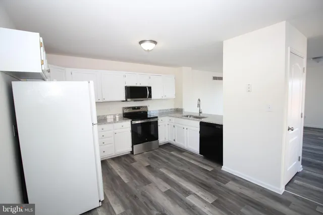 a kitchen with a refrigerator sink and white cabinets