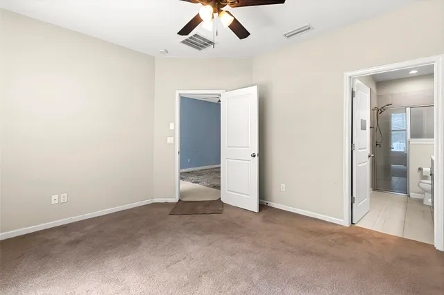 an empty room with a ceiling fan and a bathroom