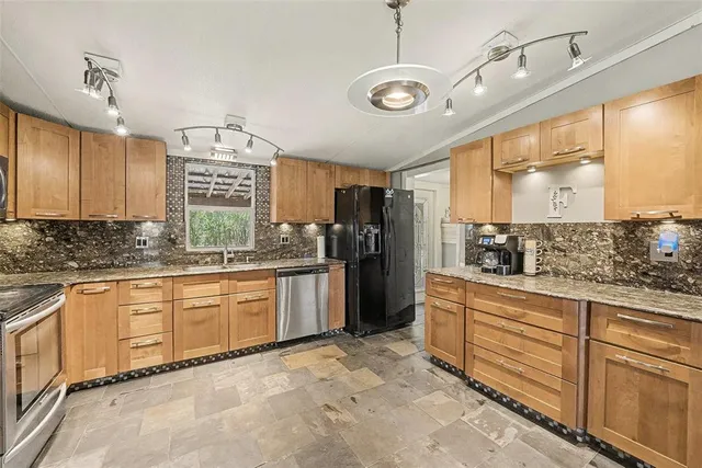 a large kitchen with stainless steel appliances kitchen island granite countertop a refrigerator and microwave