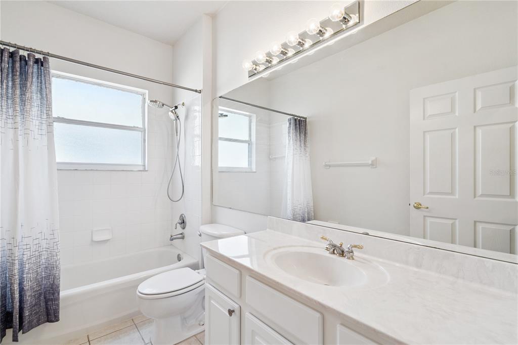 3823 Beacon Ridge Way Clermont, FL 34711 - Photo 24 of 57 a bathroom with a granite countertop sink a toilet a mirror and shower