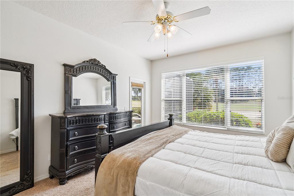 3823 Beacon Ridge Way Clermont, FL 34711 - Photo 31 of 57 a bedroom with a bed a dresser and large windows