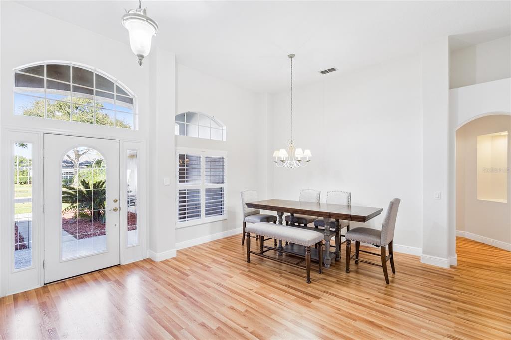 3823 Beacon Ridge Way Clermont, FL 34711 - Photo 7 of 57 a dining room with wooden floor a chandelier a glass table and chairs
