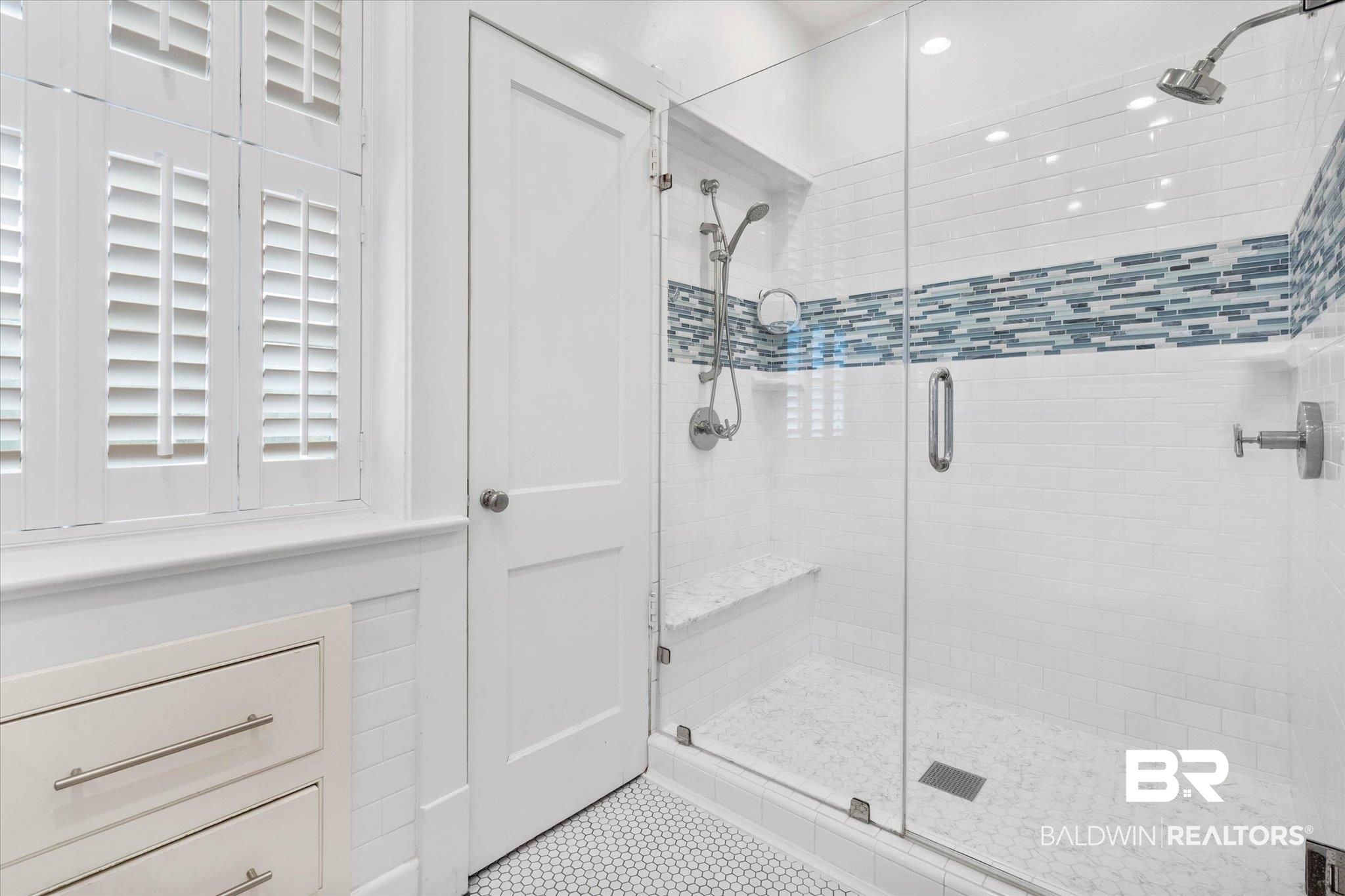 3863 Old Shell Road Mobile, AL 36608 - Photo 25 of 48 Shower enclosure featuring a frameless glass door, a tiled bench, and a mosaic tile accent band