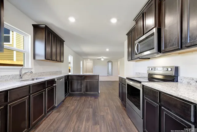 a kitchen with stainless steel appliances granite countertop wooden cabinets a sink dishwasher a stove and a granite counter top