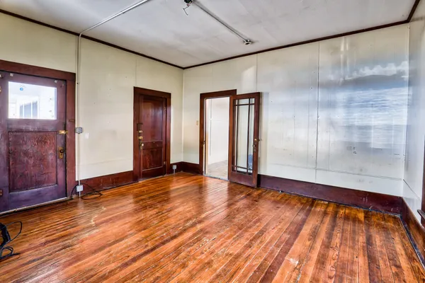 a view of an empty room with wooden floor and a window