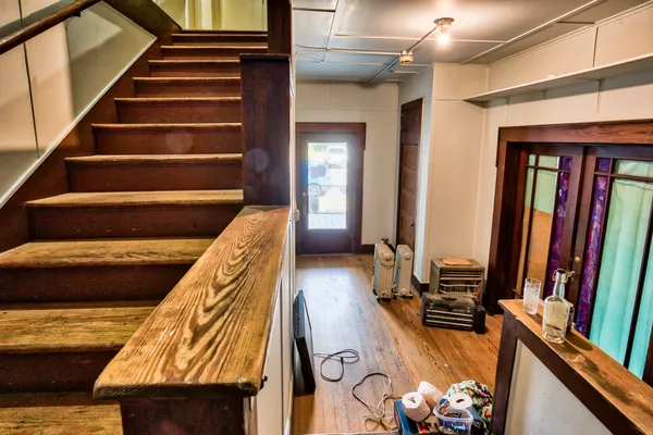 a view of a living room with wooden floor and stairs
