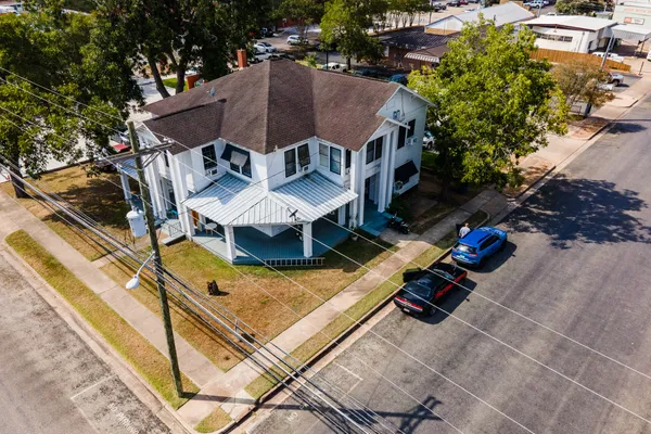 an aerial view of a house with swimming pool and glass top table and chairs