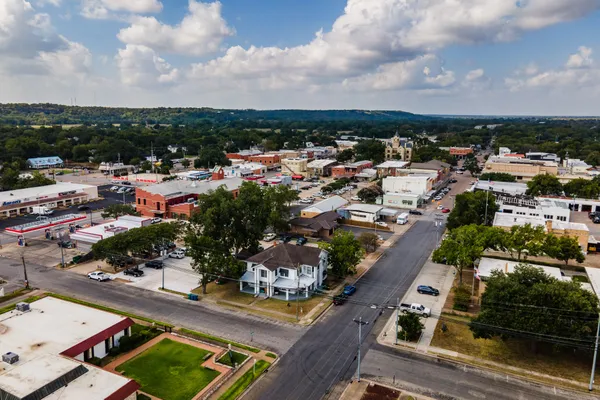 an aerial view of a house with swimming pool and large trees