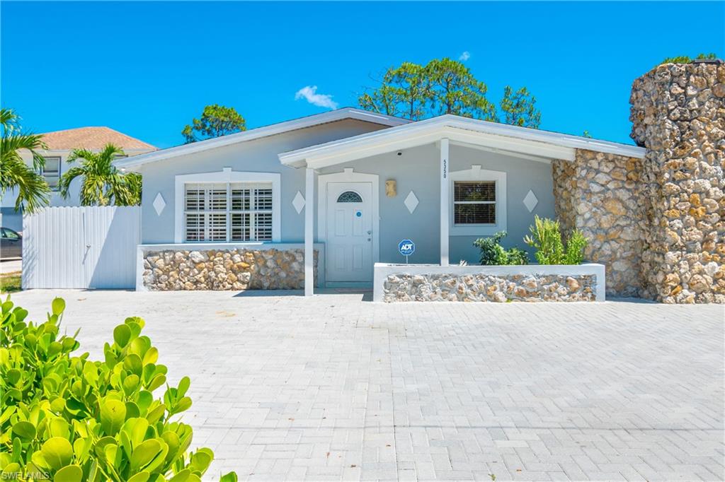 a view of a house with a yard and potted plants