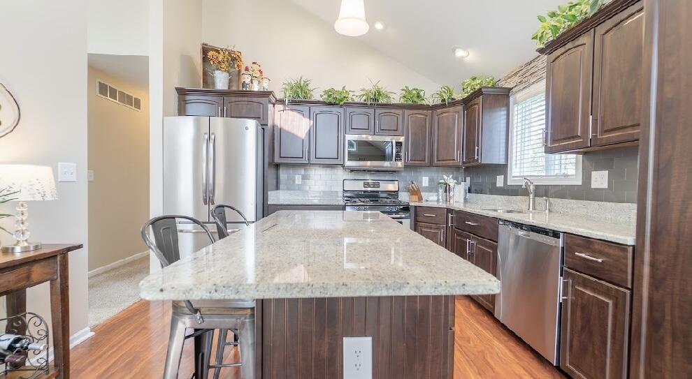 9166 Maple Court St. John, IN 46373 - Photo 12 of 40 a kitchen with kitchen island granite countertop a sink a counter top space appliances and cabinets