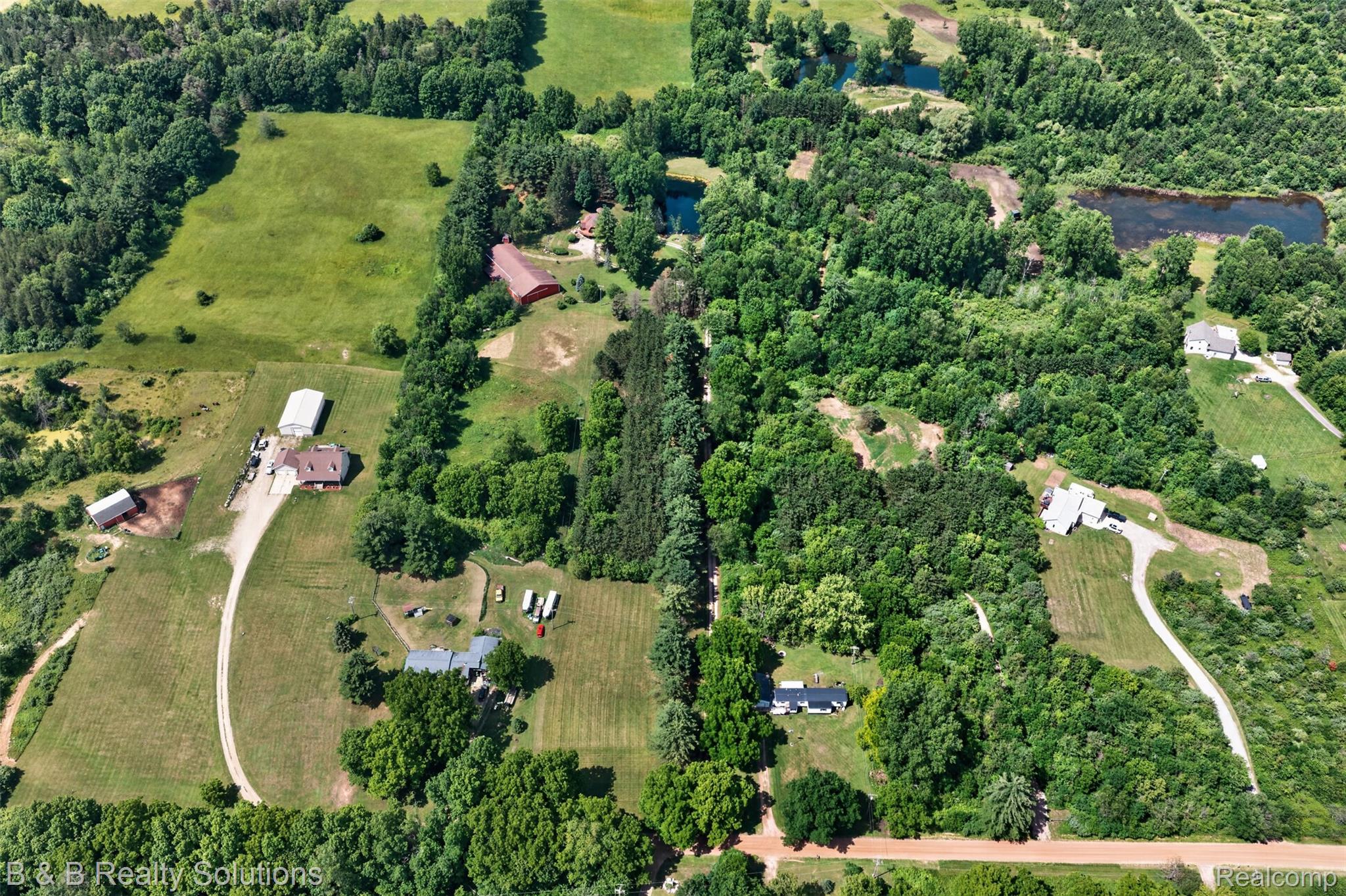 5544 Piersonville Road Columbiaville, MI 48421 - Photo 16 of 49 Expansive aerial showcasing multiple properties set within a wooded landscape with open fields and natural water features